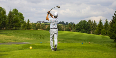 A gentleman teeing off from the greenway.